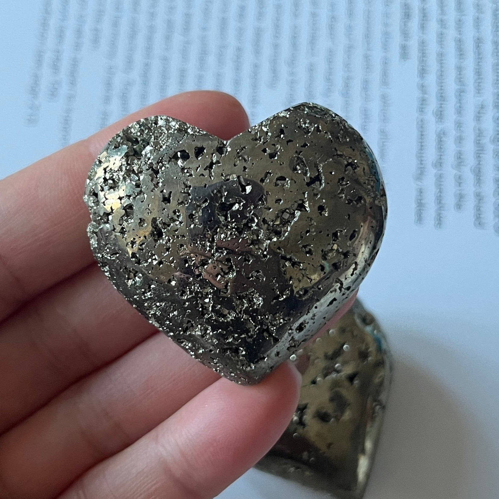 Pyramid heart held in a hand with a printed document in the background