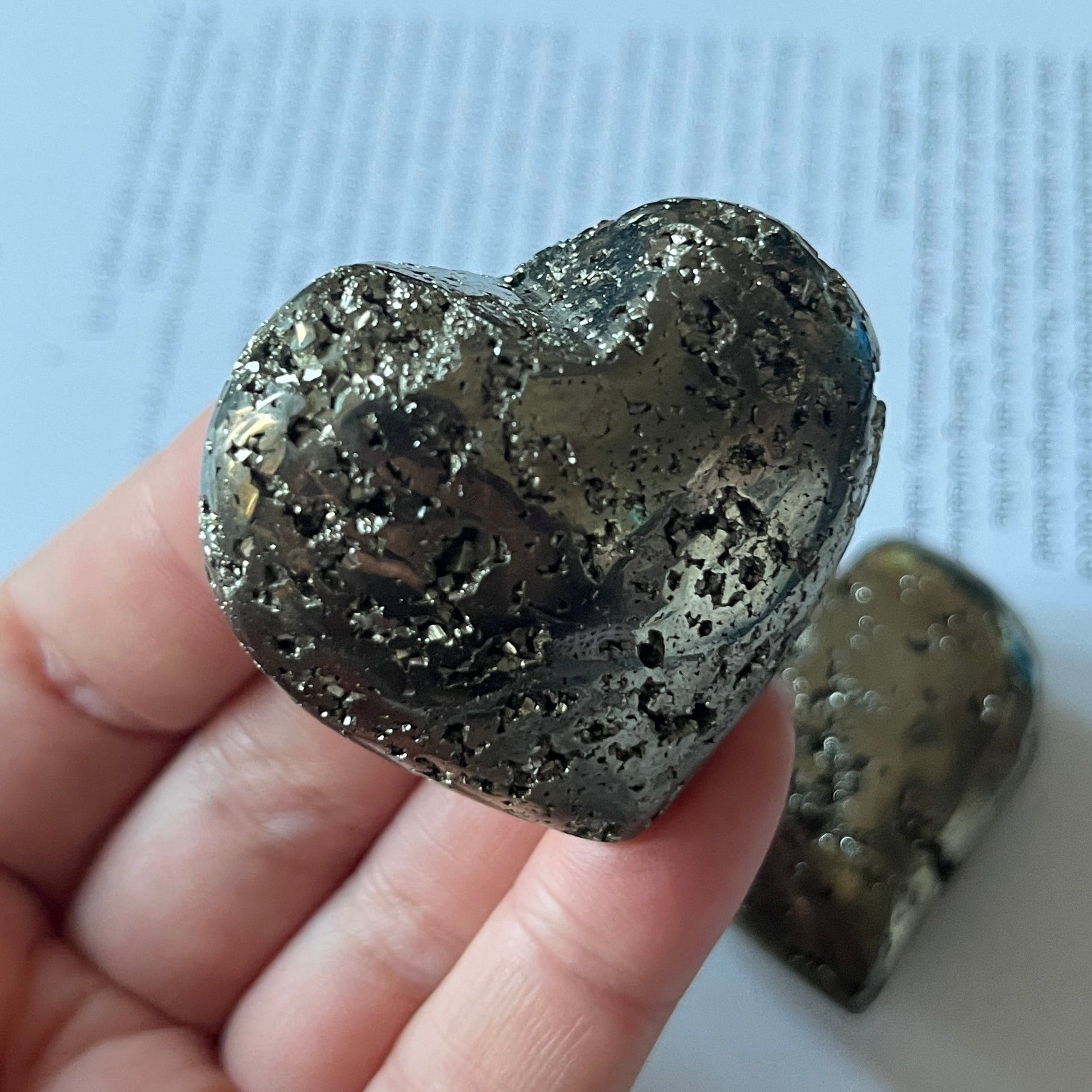 Pyramid heart held in a hand with a printed document in the background