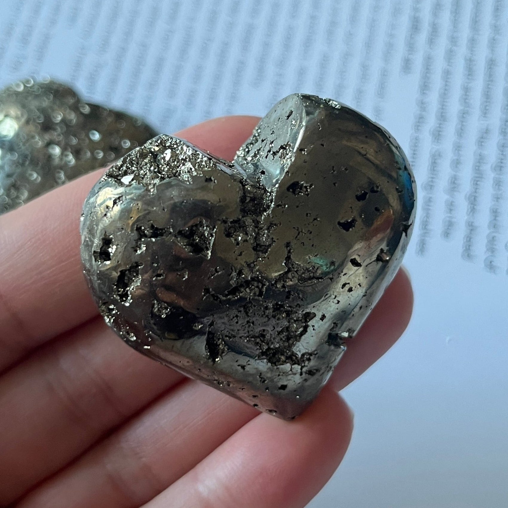 Pyramid heart held in a hand with a printed document in the background