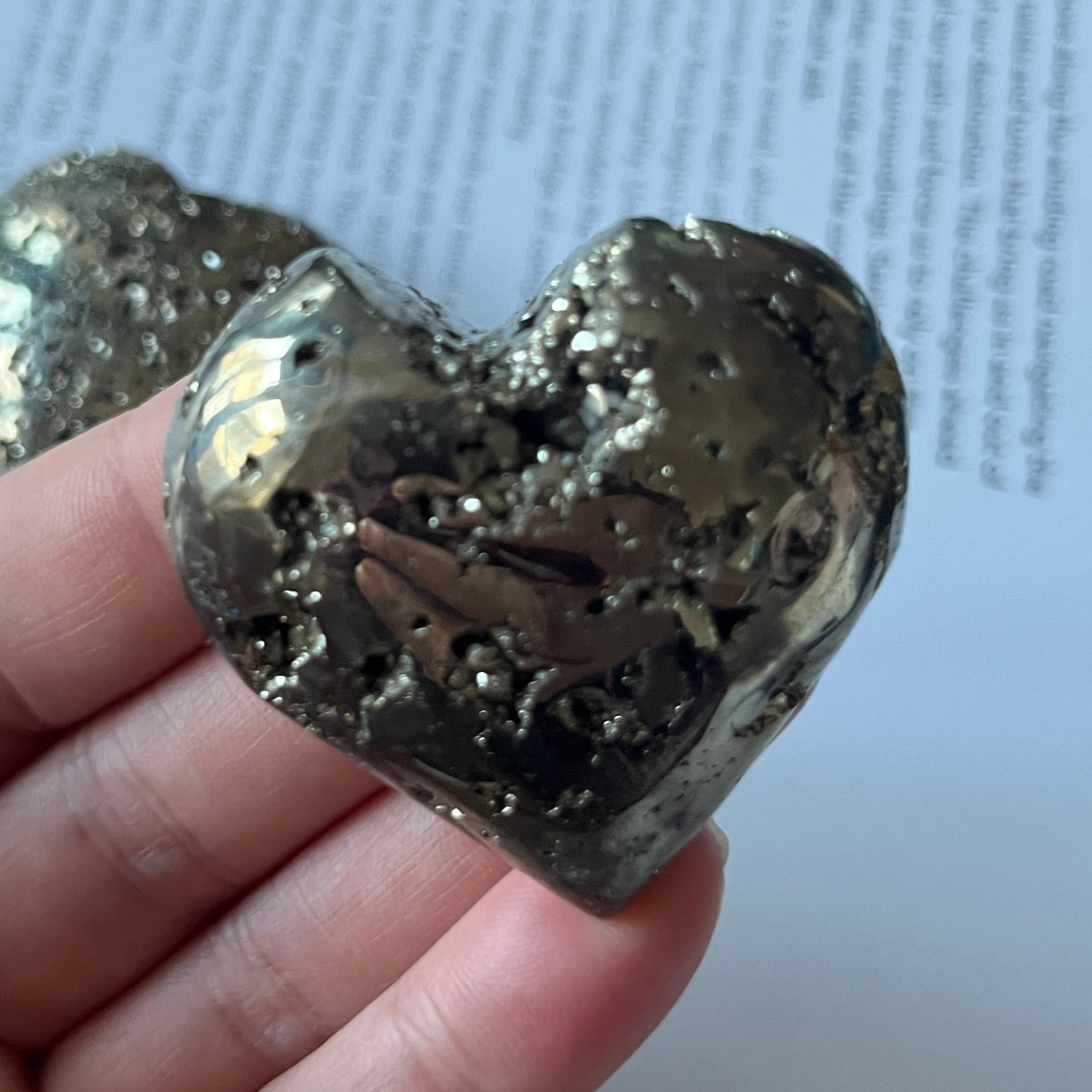 Pyramid heart held in a hand with a printed document in the background