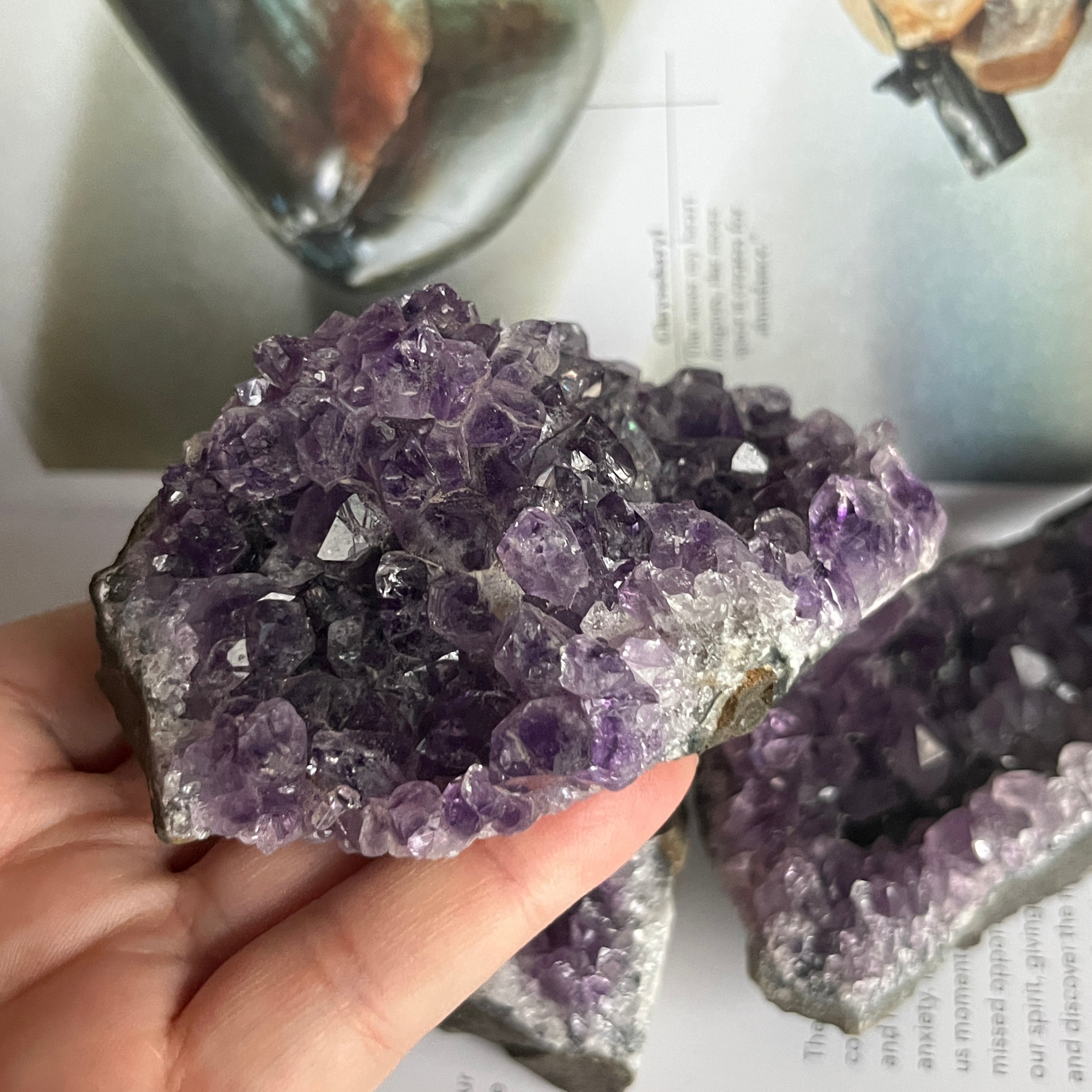 Amethyst crystal cluster held by a hand on a magazine background