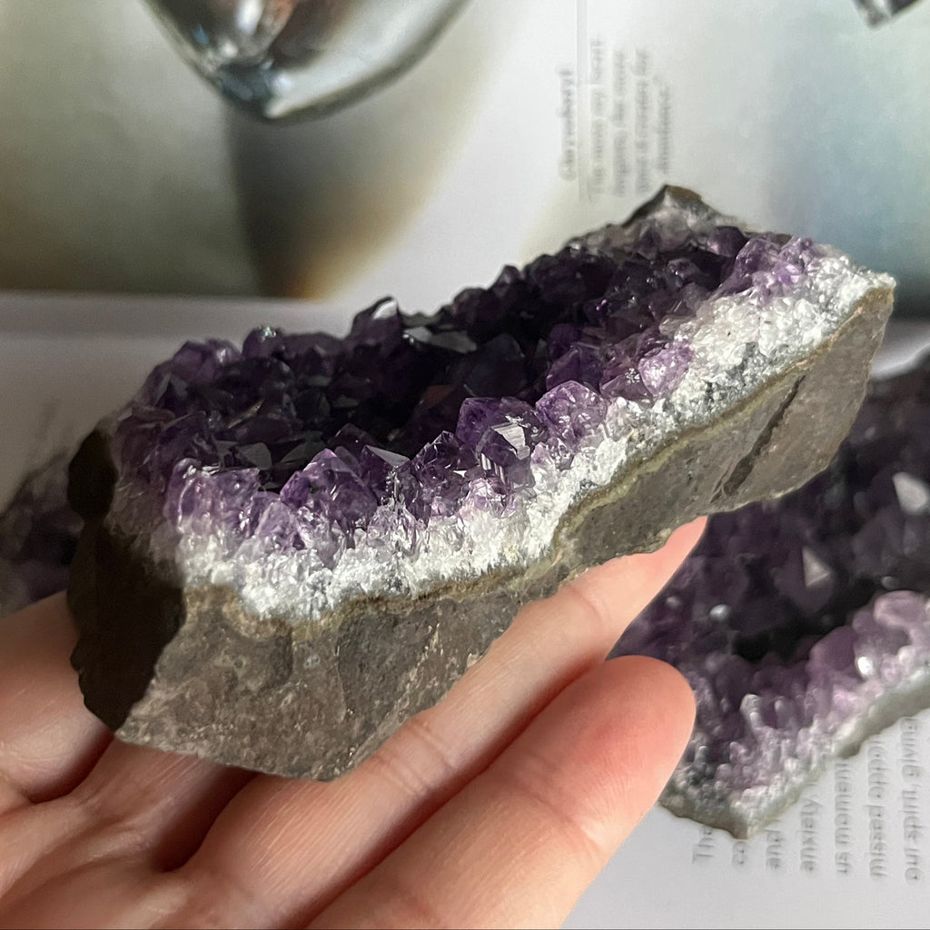 Amethyst crystal being held by a hand with a blurred background