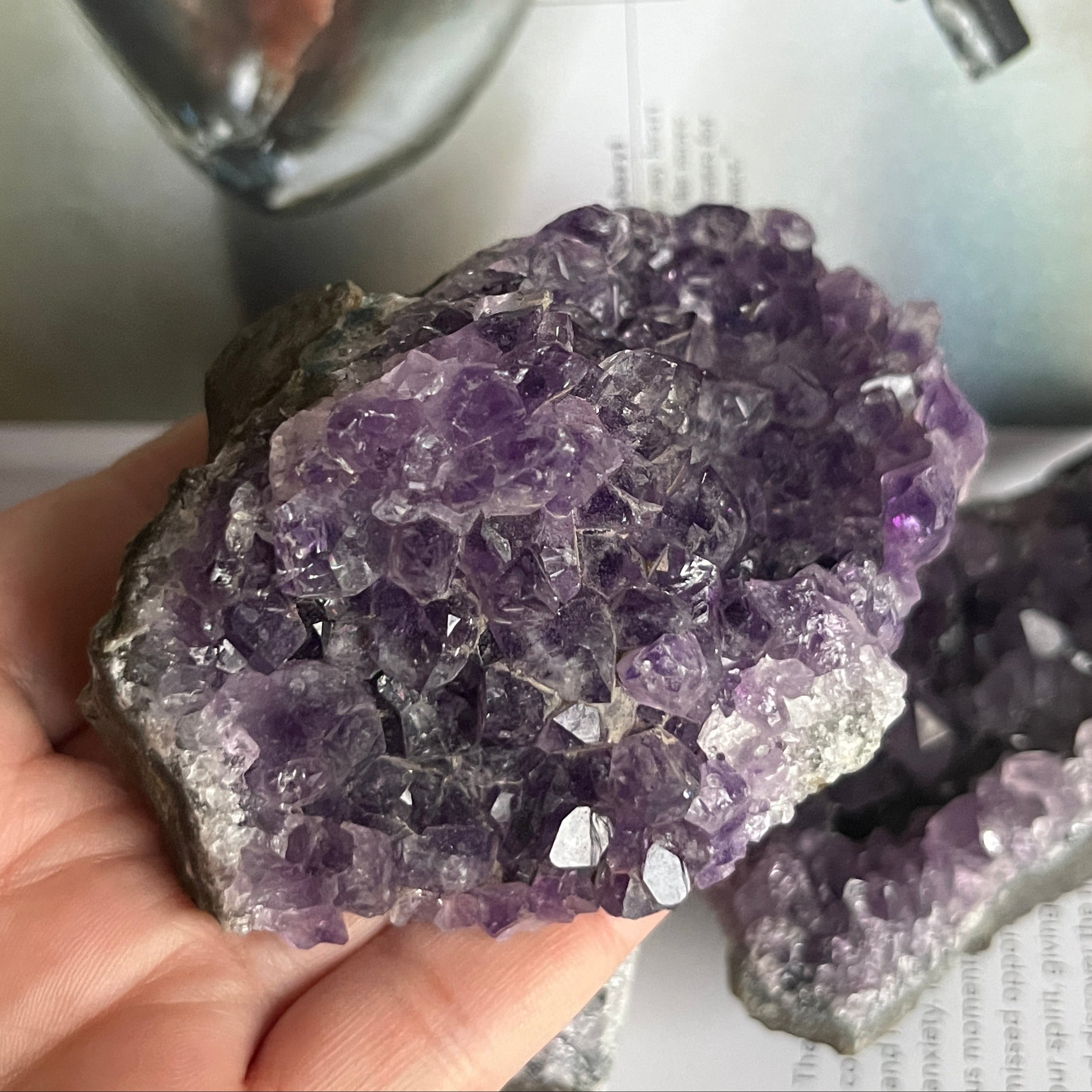 Amethyst crystal cluster held in a hand with a blurred background