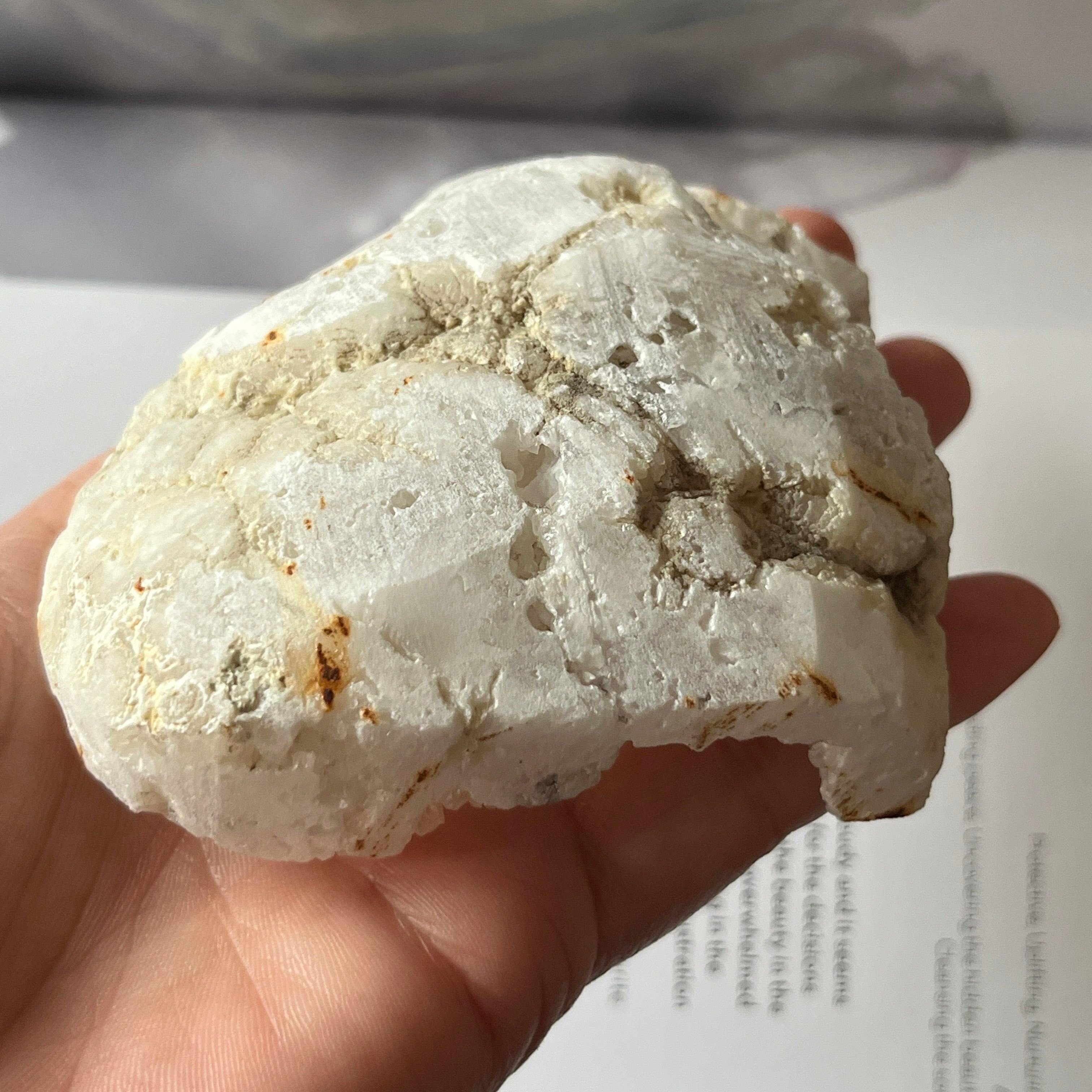 Heart-shaped white crystal geode held by a hand on an open book